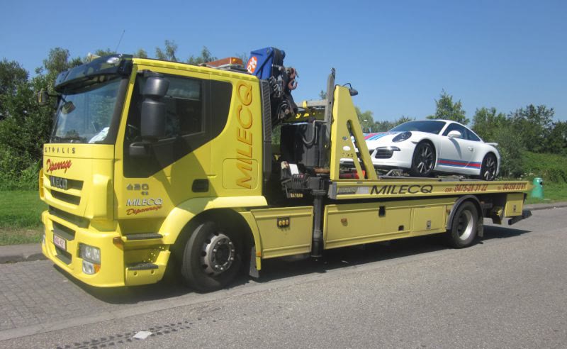 Camion de dépannage jaune Milecq transportant une Porsche 911 sur son plateau, région de Fléron