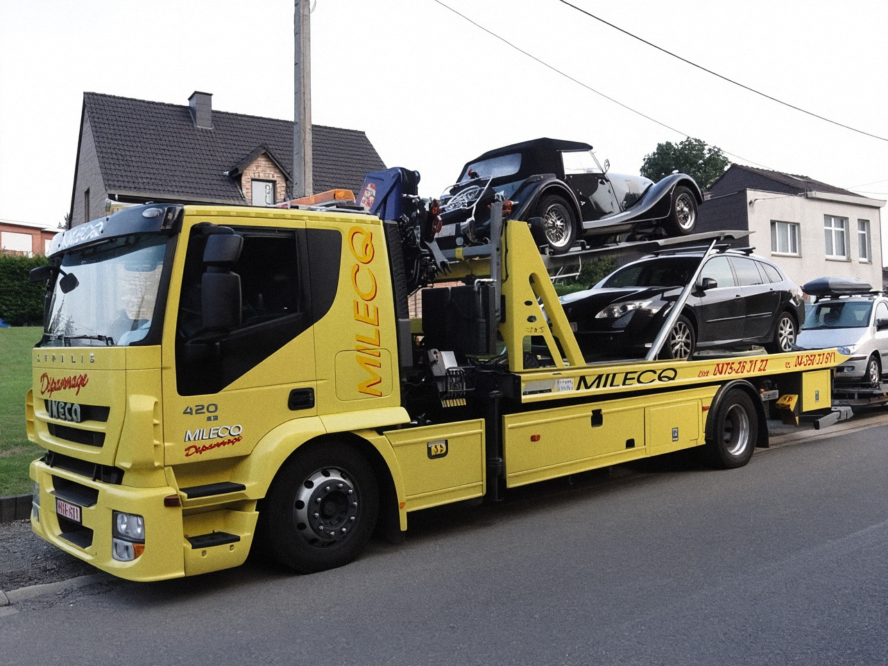 Voiture ancêtre décapotable sanglée sur le plateau du camion Milecq